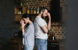 side view of young depressed couple standing back to back after quarrel at home
