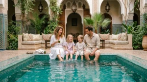 Famille détendue au bord de la piscine d'un riad traditionnel lors d'un séjour en famille à Marrakech.