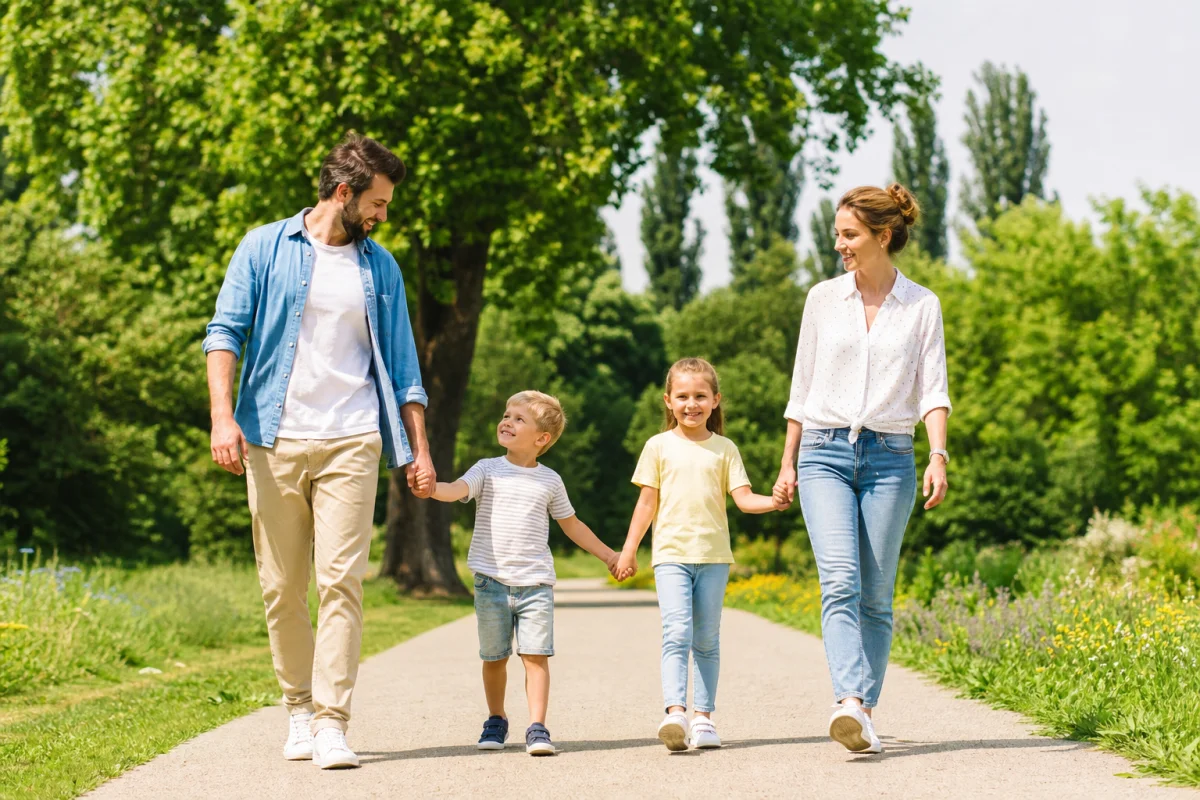 Famille souriante marchant dans un parc verdoyant pour une sortie en famille gratuite en Île-de-France.
