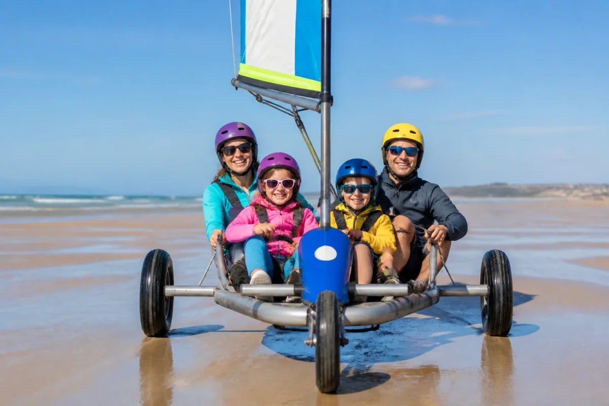 Famille souriante pratiquant le char à voile sur la plage de sable fin à Berck lors d'une journée ensoleillée.